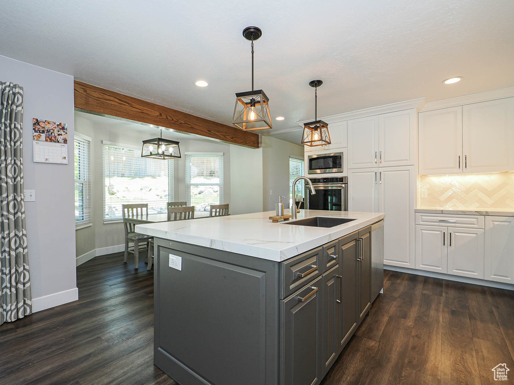 Kitchen with an island with sink, white cabinets, a sink, gray cabinetry, and stainless steel appliances
