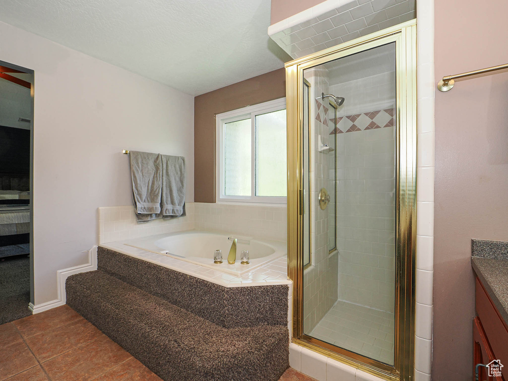 Ensuite bathroom featuring a garden tub, vanity, tile patterned flooring, a shower stall, and ensuite bath