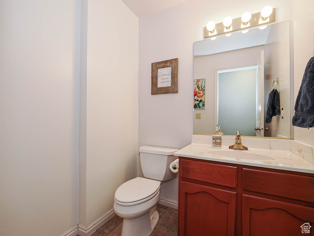 Half bath with baseboards, vanity, and toilet