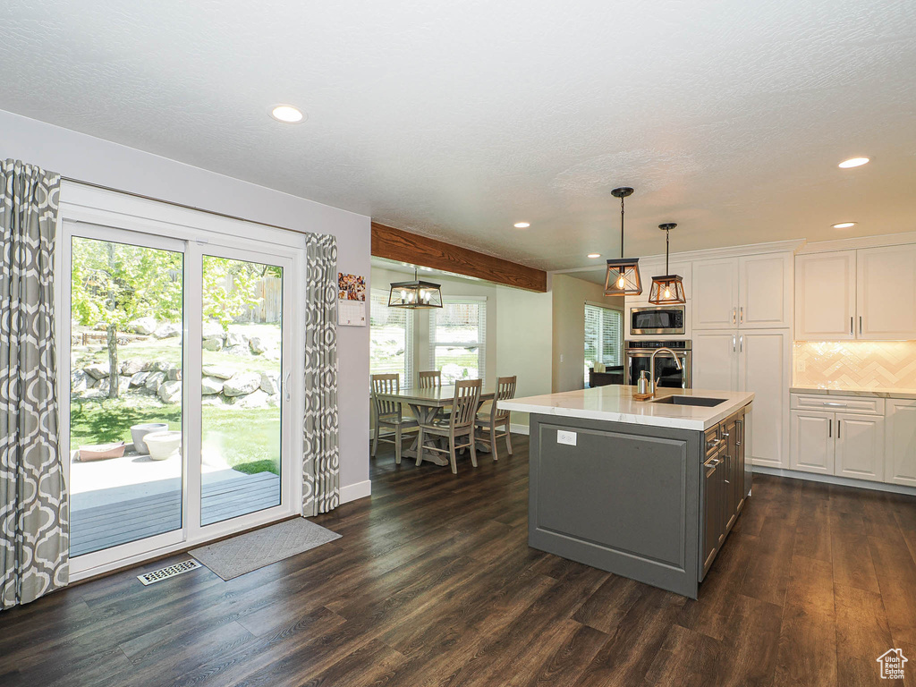 Kitchen with a sink, light countertops, white cabinets, stainless steel appliances, and dark wood-type flooring
