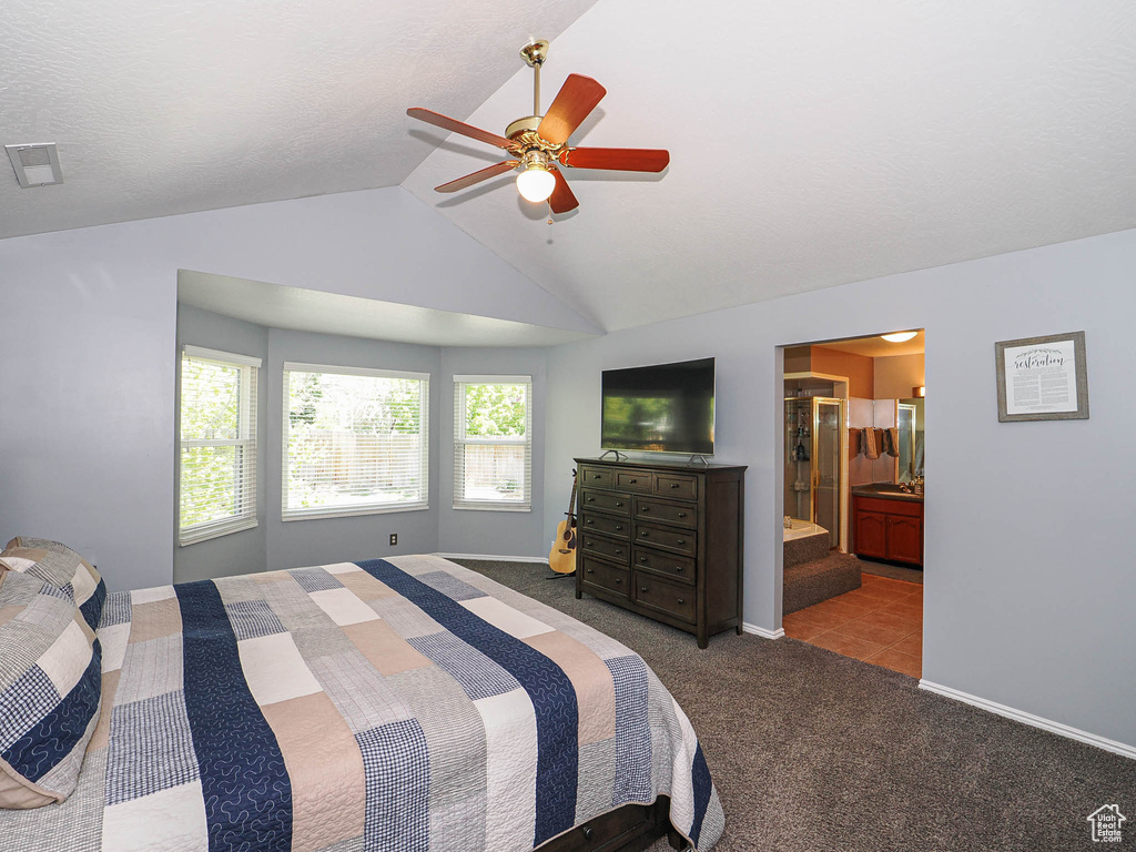 Bedroom with ensuite bath, carpet, baseboards, lofted ceiling, and visible vents