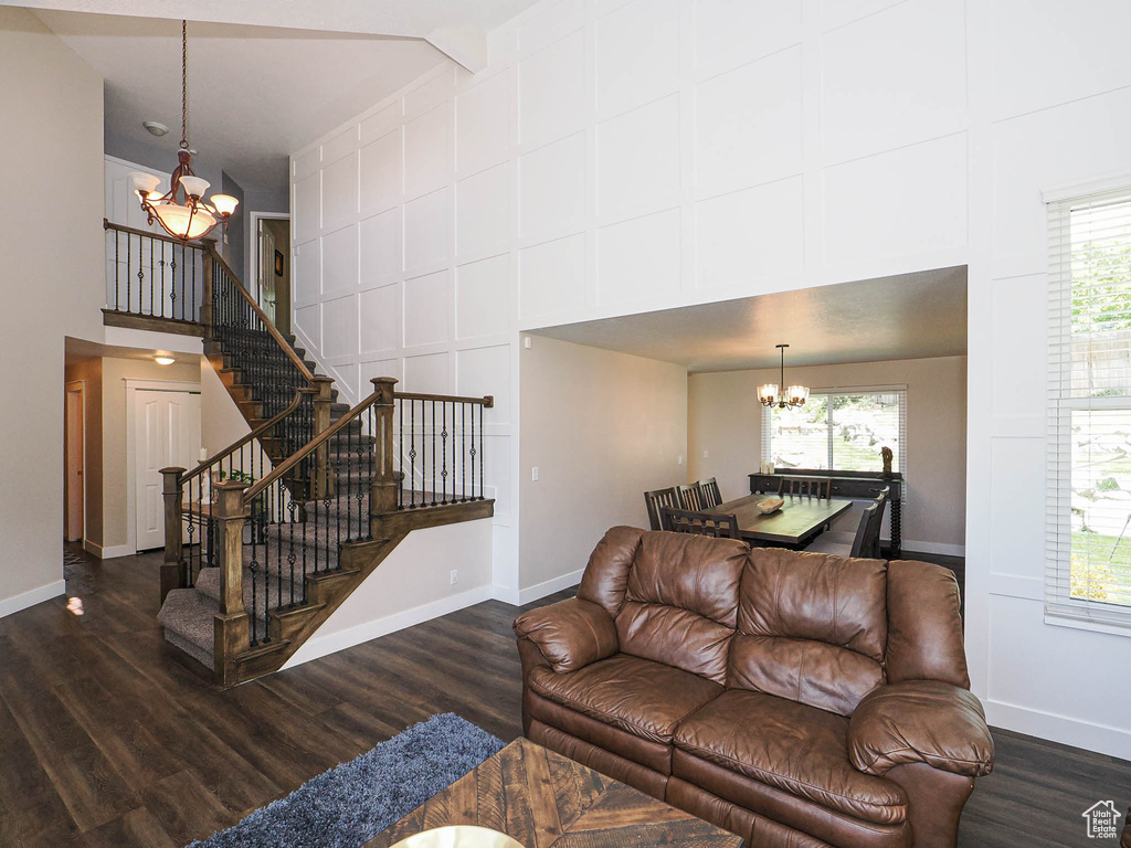 Living area featuring a towering ceiling, wood finished floors, a notable chandelier, and stairway