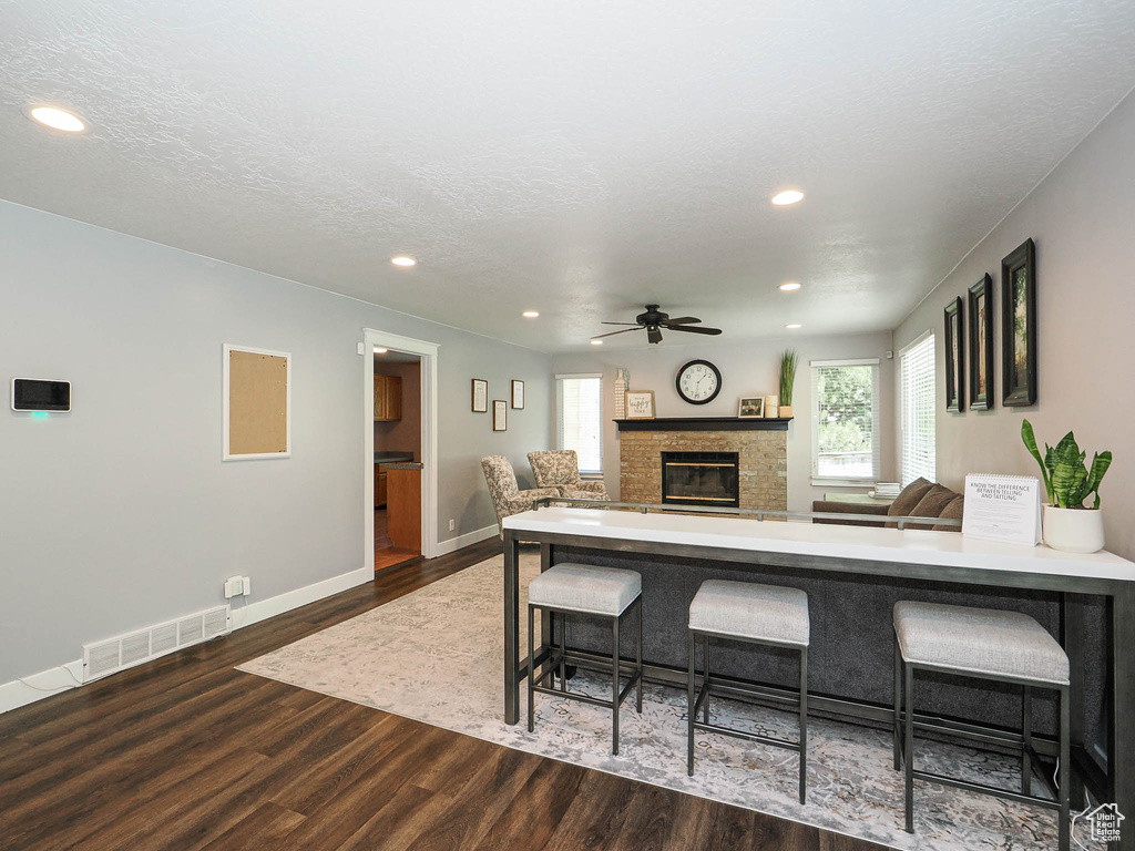 Living room with visible vents, a glass covered fireplace, wood finished floors, and a wealth of natural light