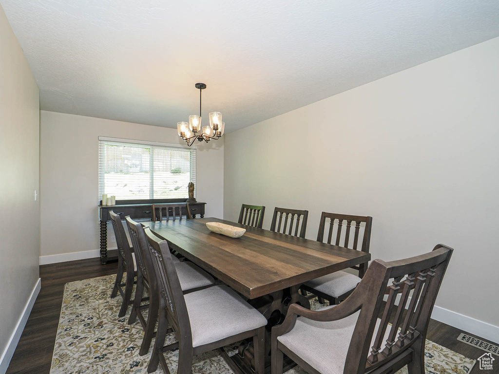 Dining area with baseboards, an inviting chandelier, dark wood-style floors, and visible vents