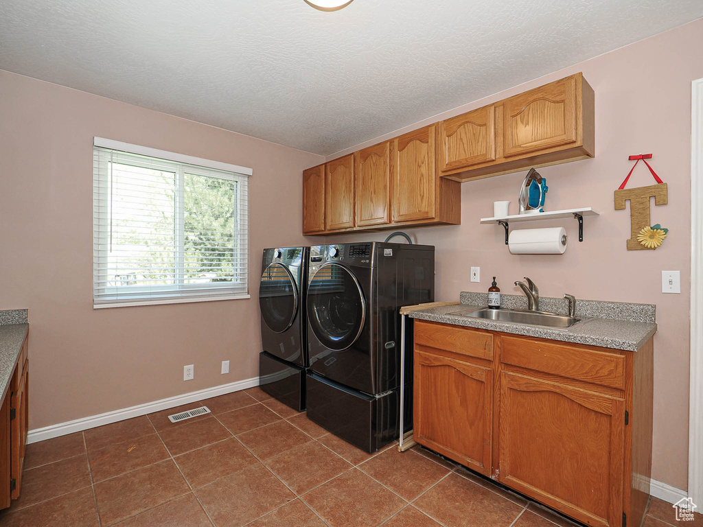 Laundry room featuring cabinet space, a sink, separate washer and dryer, baseboards, and visible vents