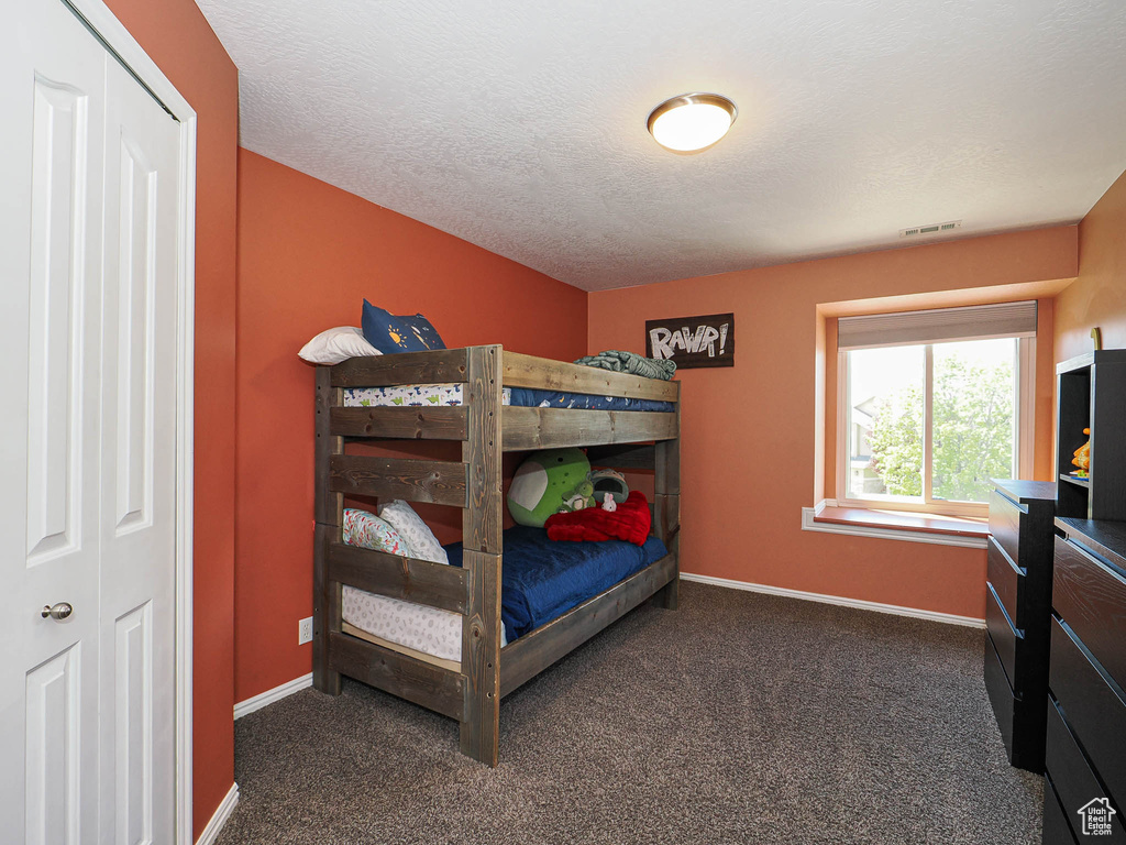 Bedroom with visible vents, baseboards, and dark colored carpet