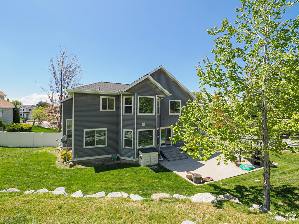 Rear view of house with a lawn, a patio, and fence