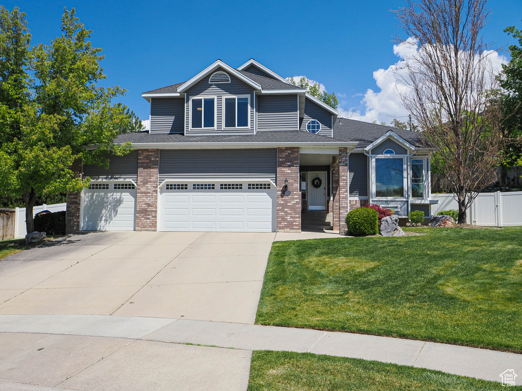 Craftsman inspired home with fence, an attached garage, a front lawn, brick siding, and driveway