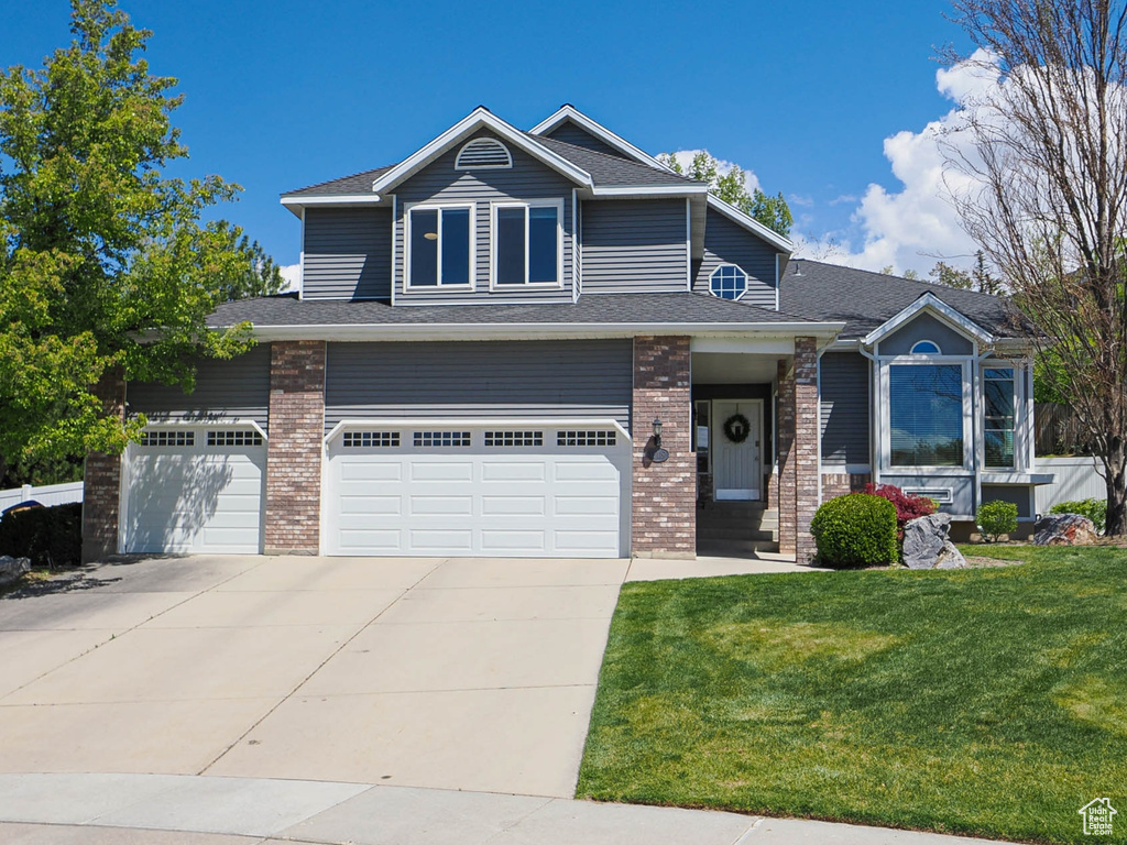 Craftsman inspired home with fence, an attached garage, a front lawn, brick siding, and driveway