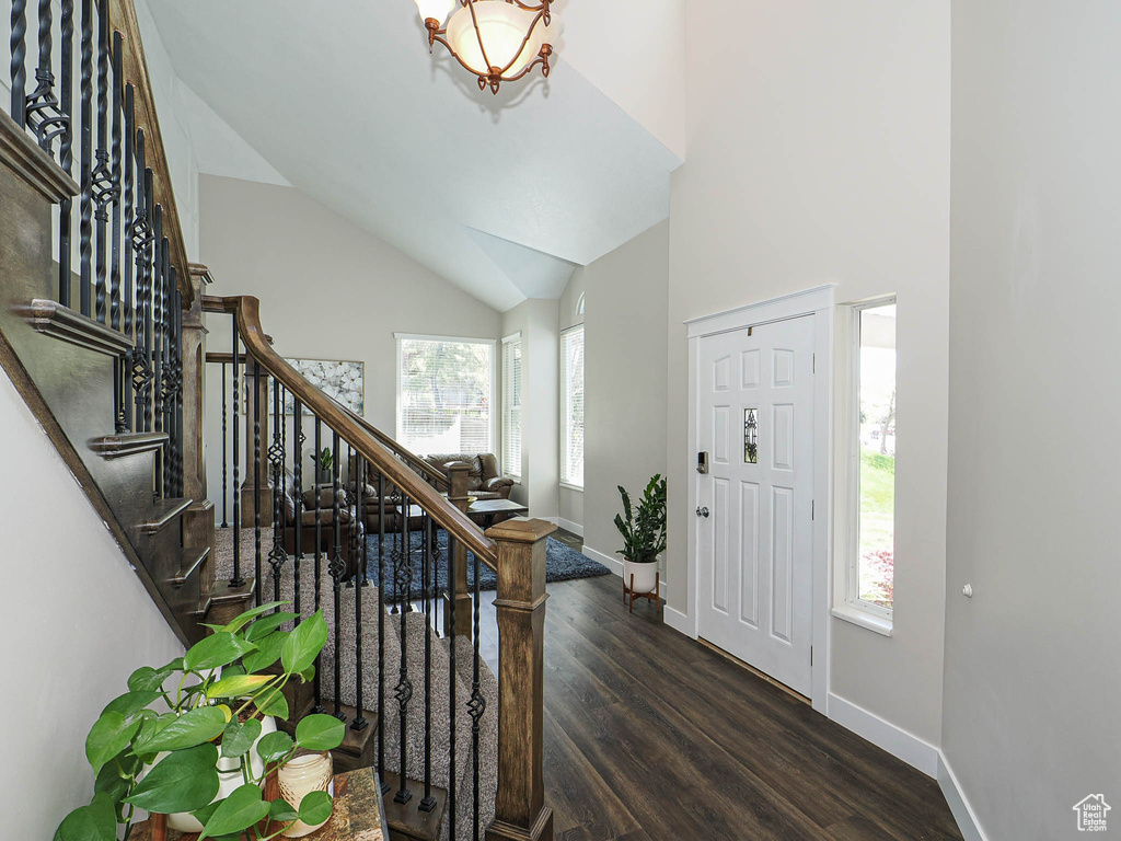Foyer with stairway, baseboards, high vaulted ceiling, and wood finished floors