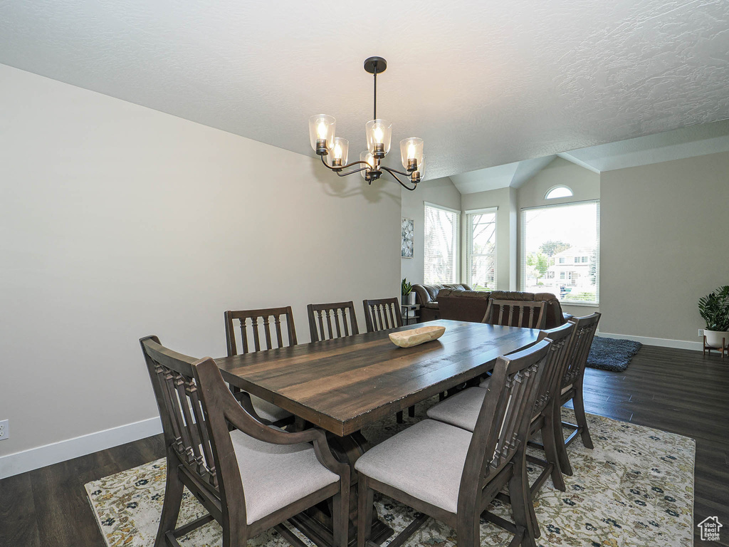 Dining area featuring baseboards, an inviting chandelier, wood finished floors, and vaulted ceiling
