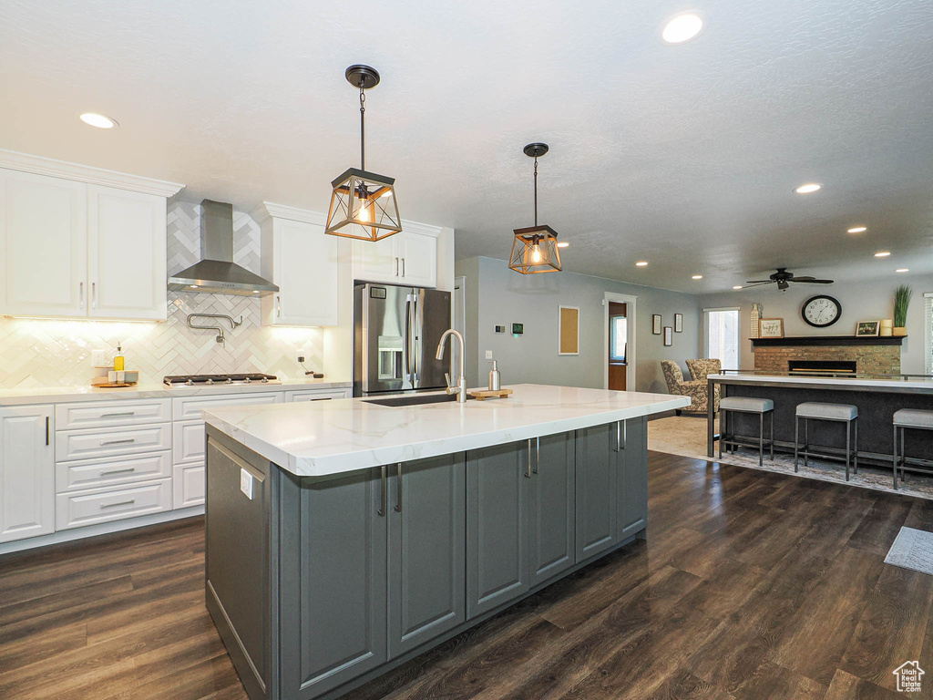 Kitchen featuring ceiling fan, recessed lighting, gray cabinets, wall chimney exhaust hood, and appliances with stainless steel finishes