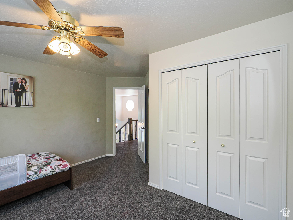 Bedroom with a closet, baseboards, a ceiling fan, and dark colored carpet