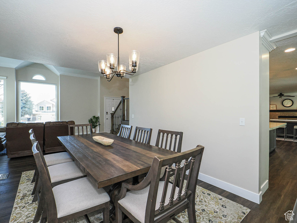 Dining space with a textured ceiling, dark wood finished floors, baseboards, an inviting chandelier, and recessed lighting