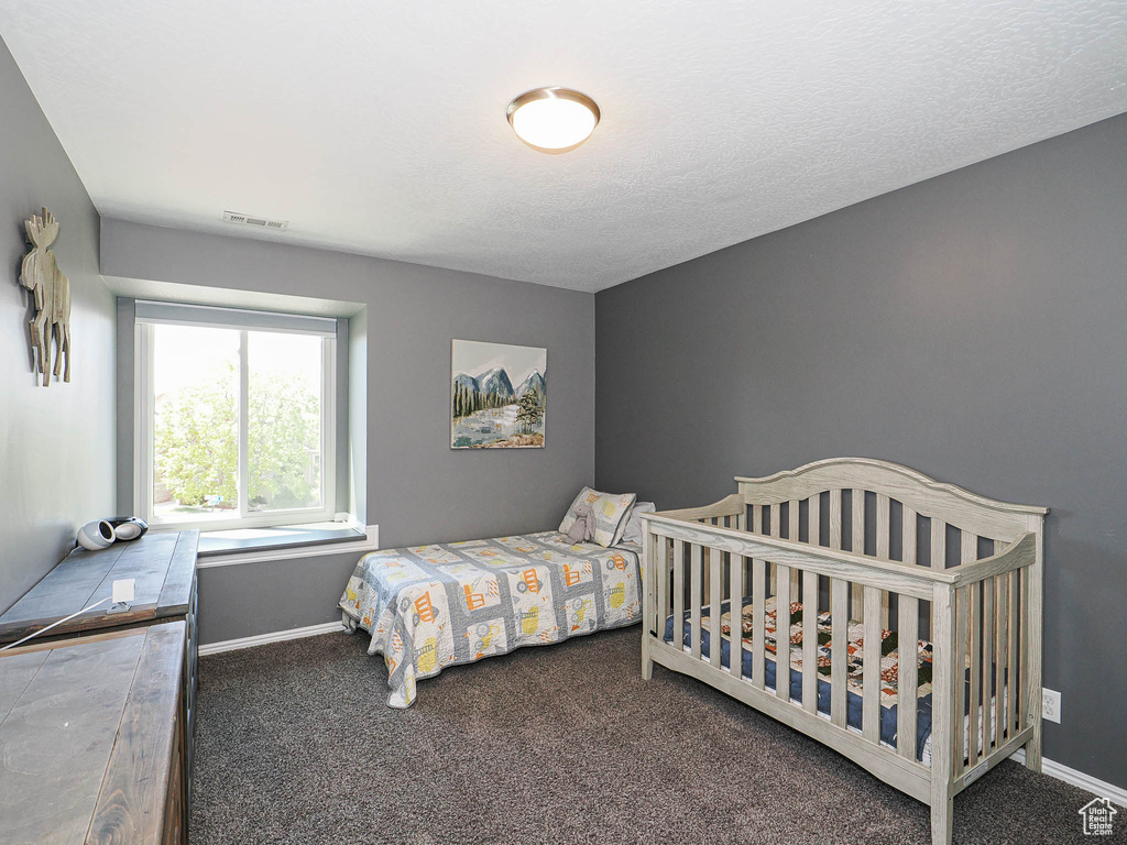 Carpeted bedroom featuring baseboards and visible vents