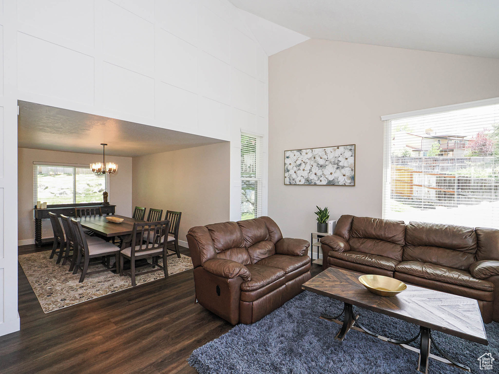 Living area with a chandelier, high vaulted ceiling, dark wood finished floors, and baseboards