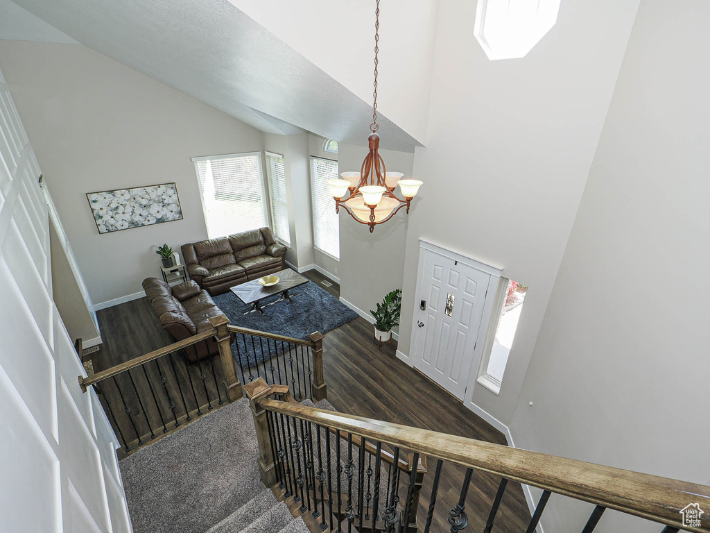 Staircase with baseboards, wood finished floors, a notable chandelier, and high vaulted ceiling