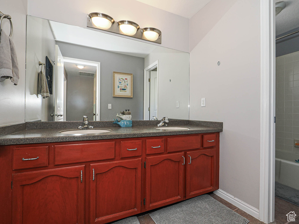 Full bathroom featuring double vanity, tile patterned floors, visible vents, and a sink
