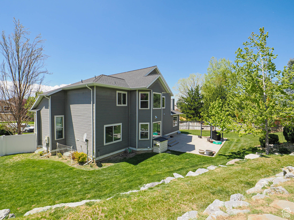 Rear view of property featuring a yard, a patio, and fence