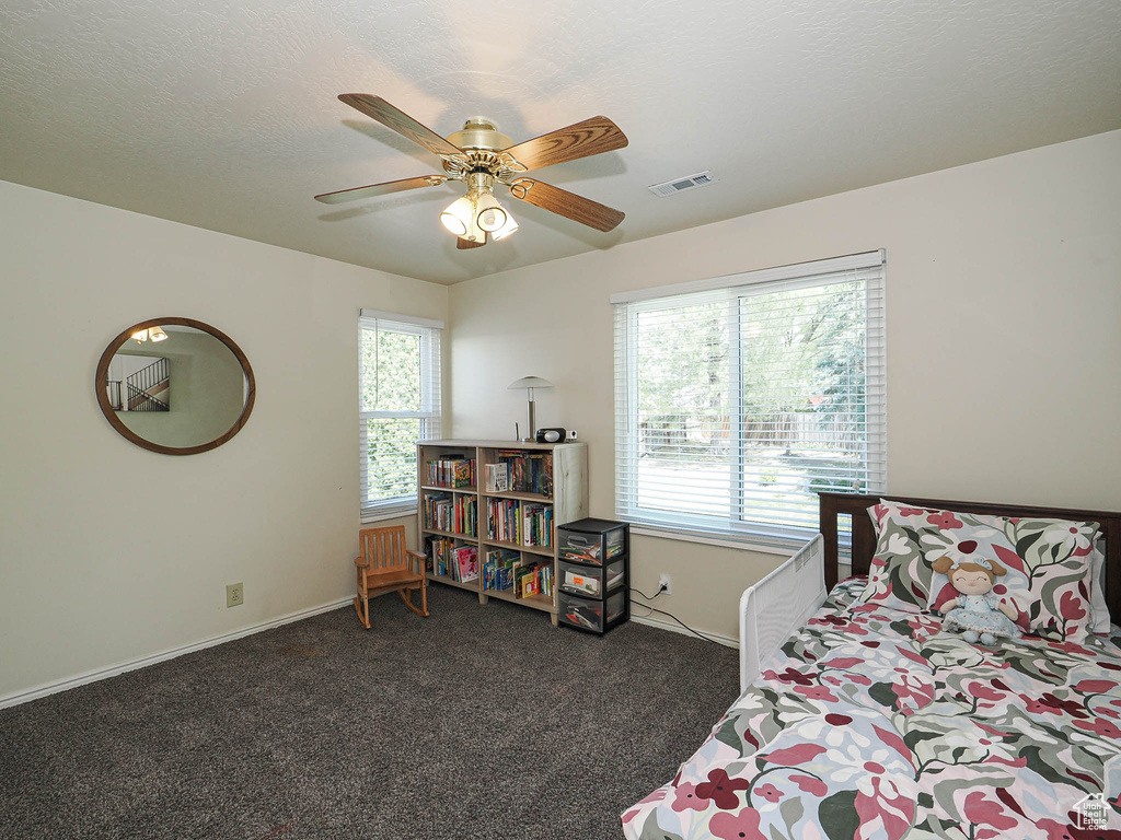 Bedroom with visible vents, baseboards, multiple windows, and dark colored carpet