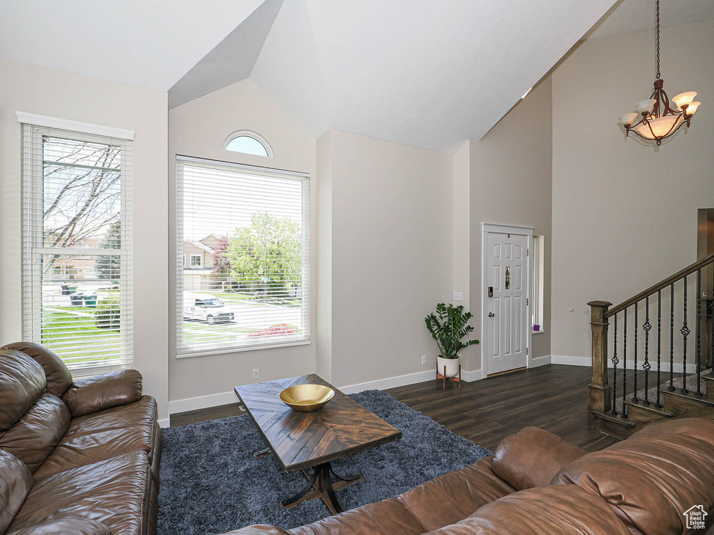 Living room featuring plenty of natural light, wood finished floors, a notable chandelier, and stairway