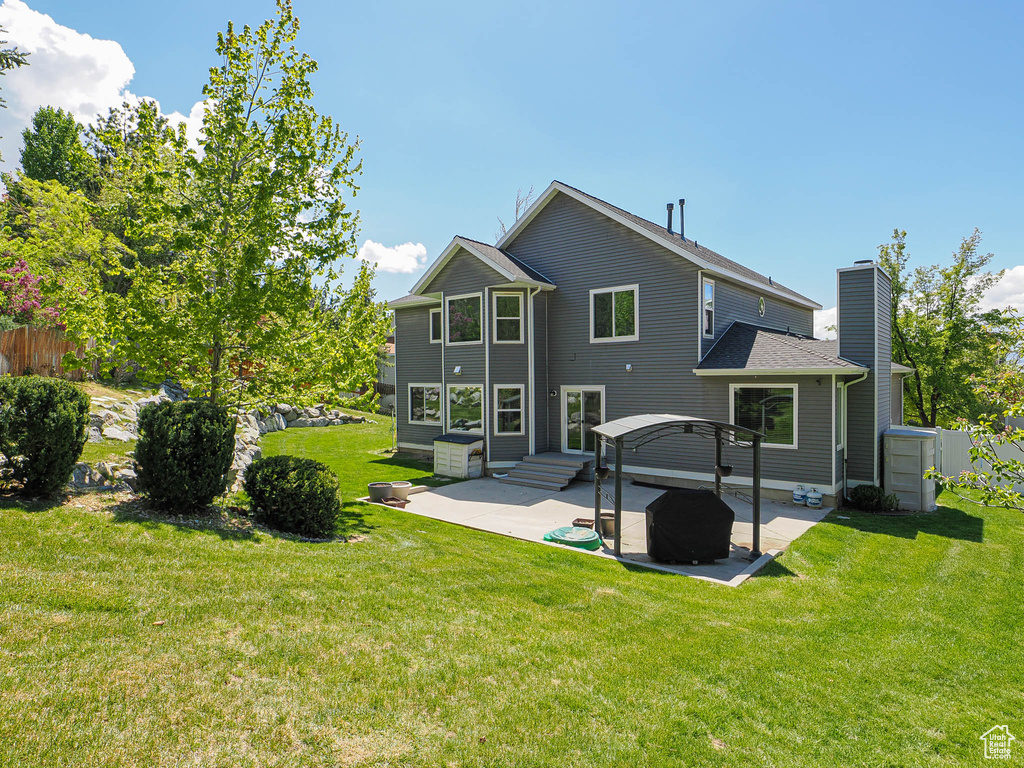 Rear view of property with a lawn, a patio, fence, and a chimney