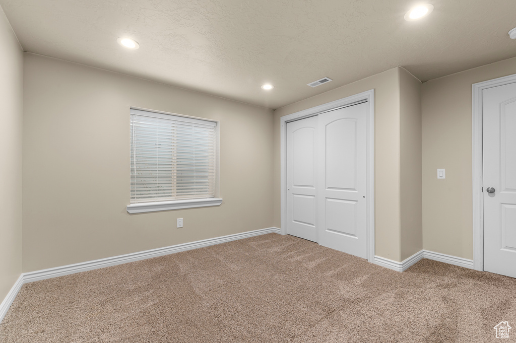 Unfurnished bedroom featuring recessed lighting, carpet, baseboards, and a closet