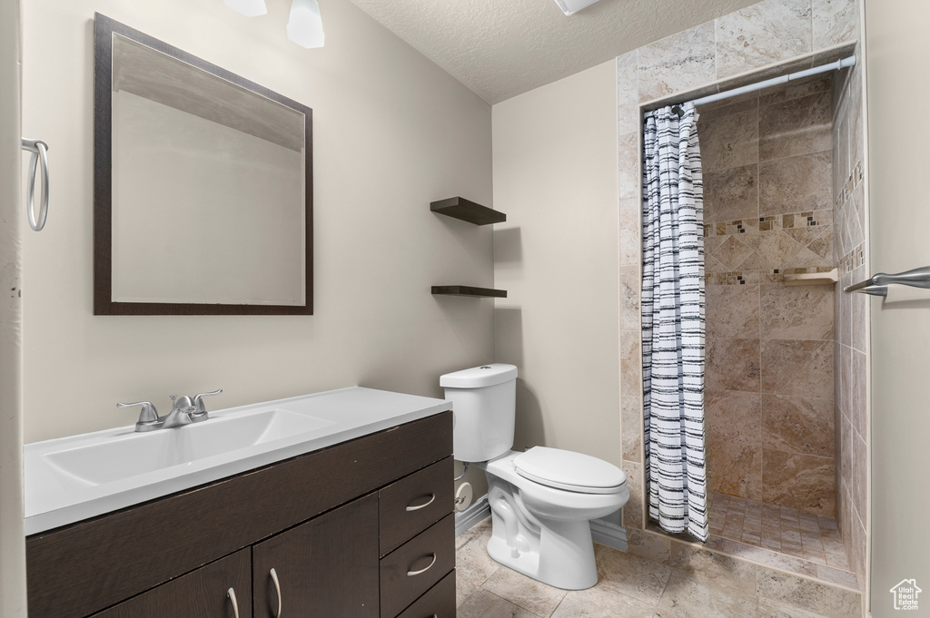Bathroom with vanity, a stall shower, toilet, and a textured ceiling