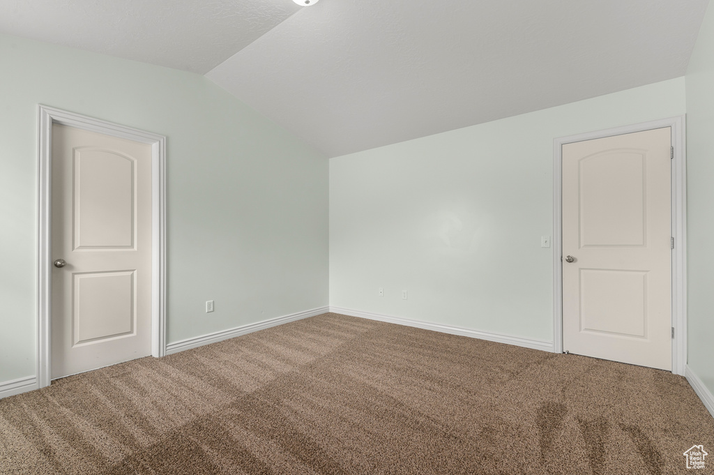Unfurnished room with baseboards, carpet, and vaulted ceiling