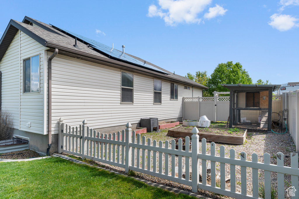 Back of house with a garden, solar panels, a lawn, central air condition unit, and a fenced backyard