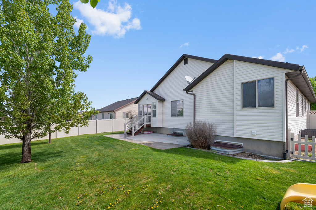 Rear view of house with fence, a patio, and a yard