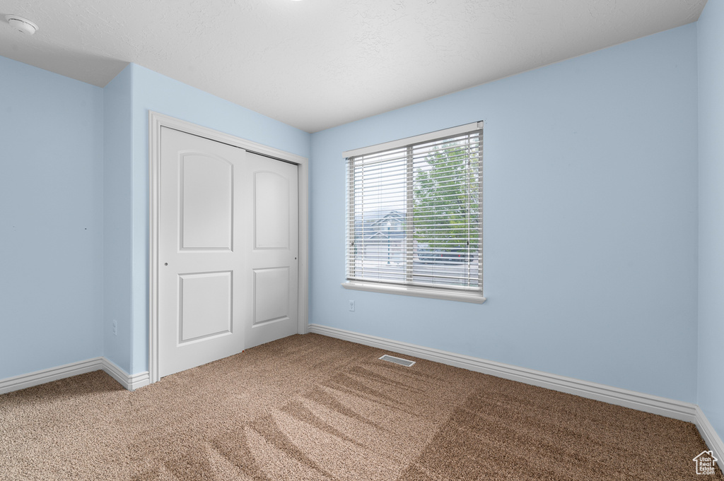 Unfurnished bedroom featuring baseboards, carpet, a closet, and visible vents