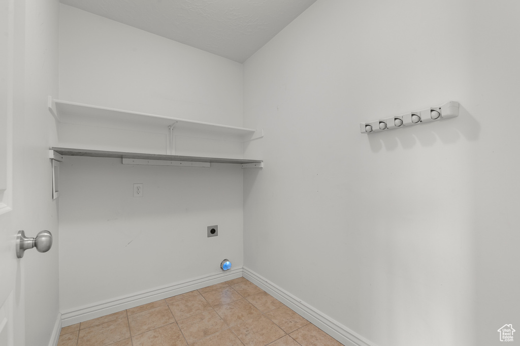 Laundry area with baseboards, light tile patterned floors, laundry area, and electric dryer hookup