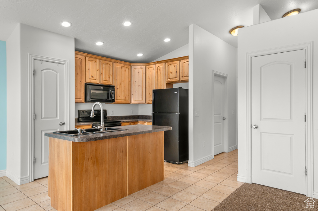 Kitchen with light tile patterned flooring, dark countertops, an island with sink, recessed lighting, and black appliances