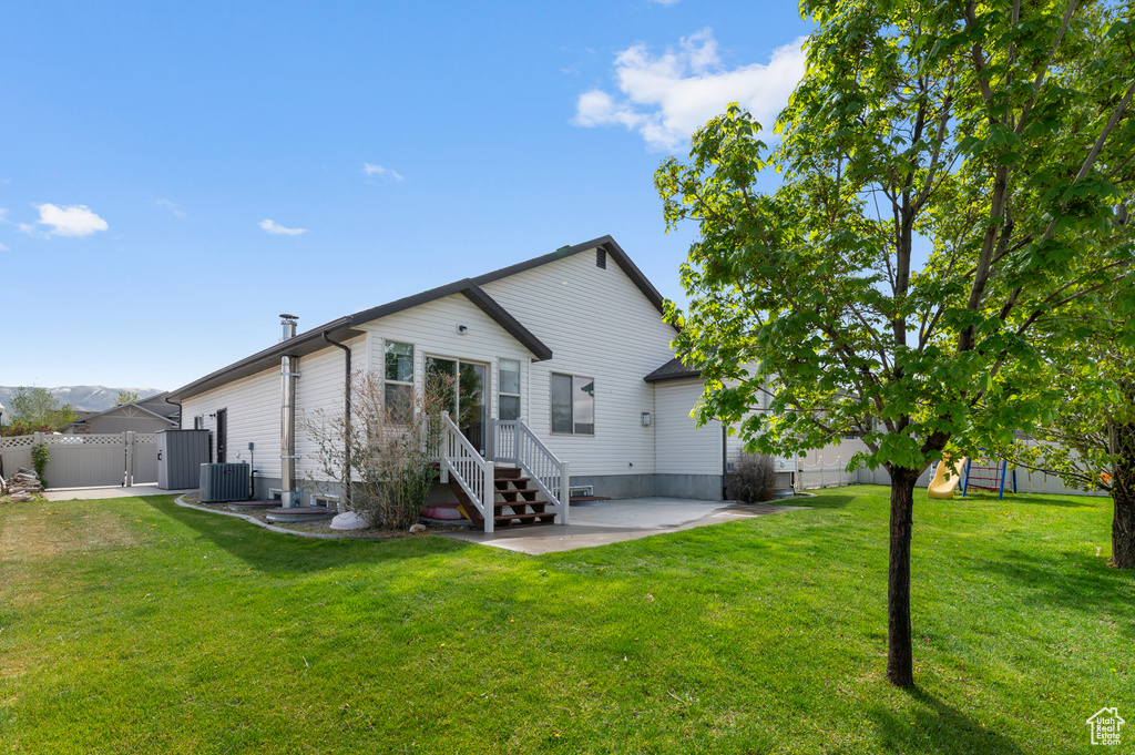 Rear view of house with fence, entry steps, a gate, a patio area, and a yard