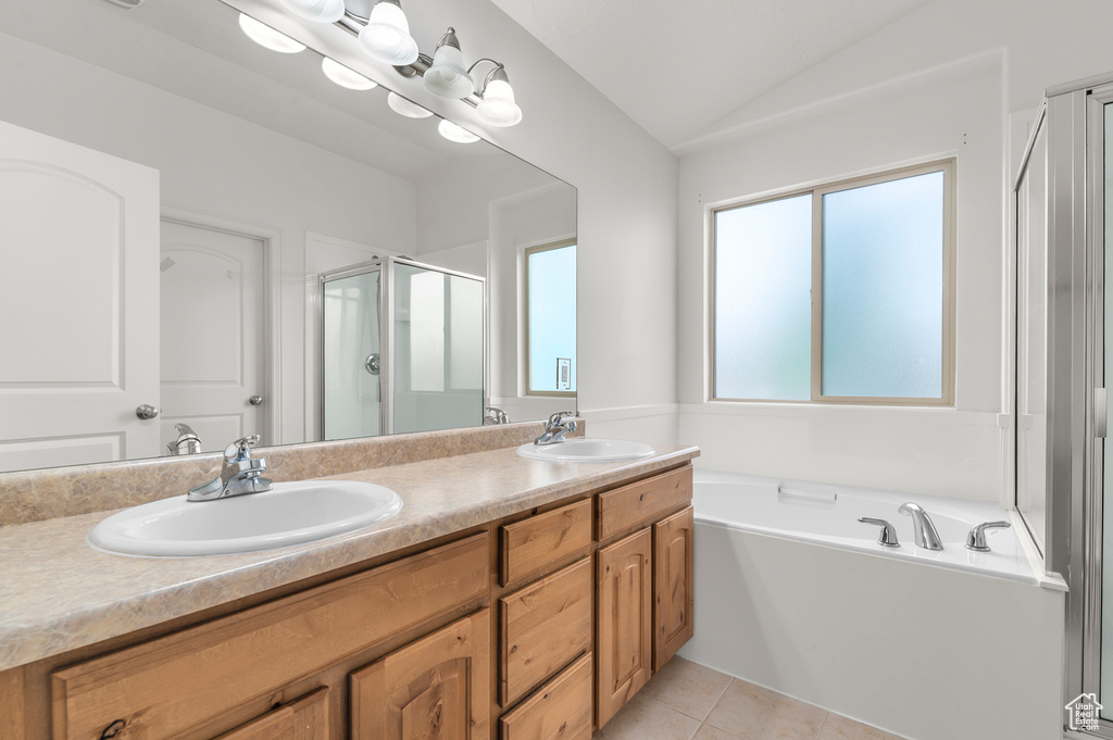 Full bathroom with double vanity, vaulted ceiling, a sink, and a stall shower