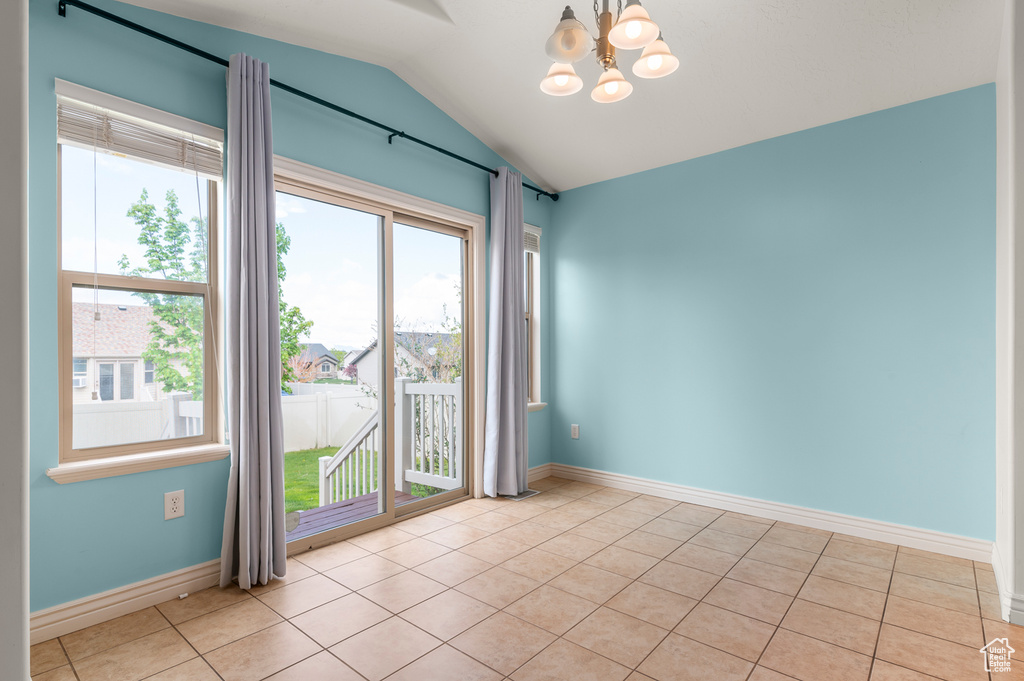 Unfurnished room with baseboards, light tile patterned floors, lofted ceiling, and a notable chandelier