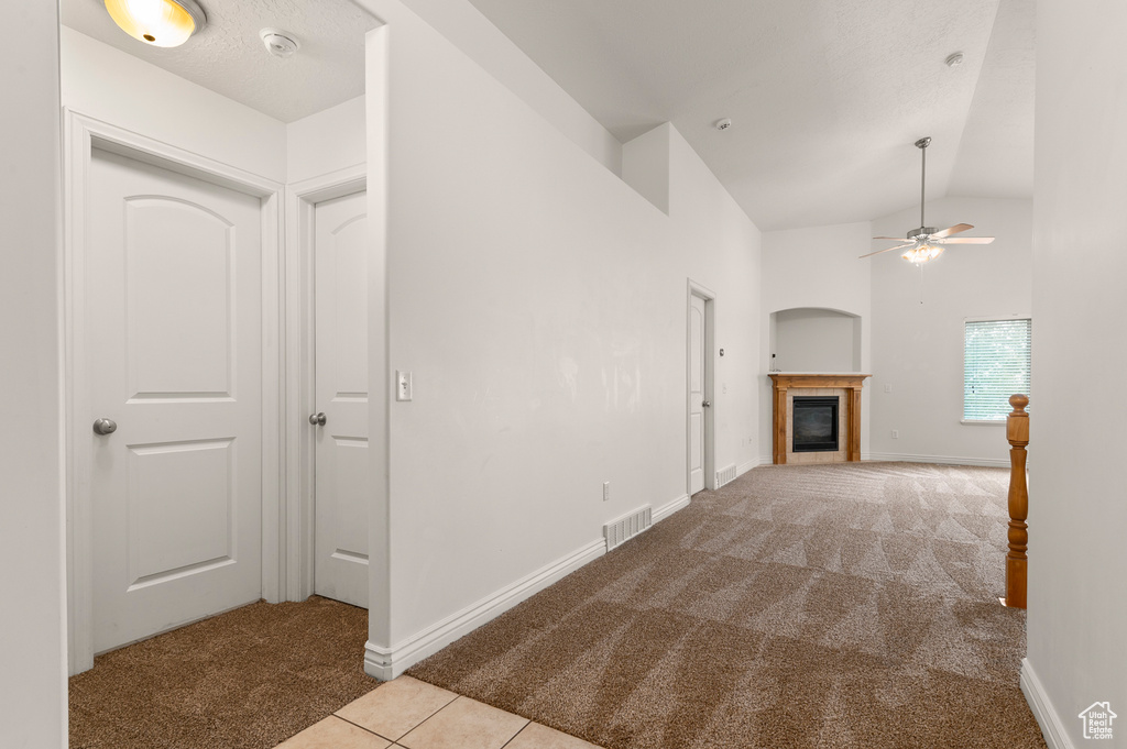 Corridor featuring visible vents, tile patterned flooring, baseboards, carpet flooring, and vaulted ceiling