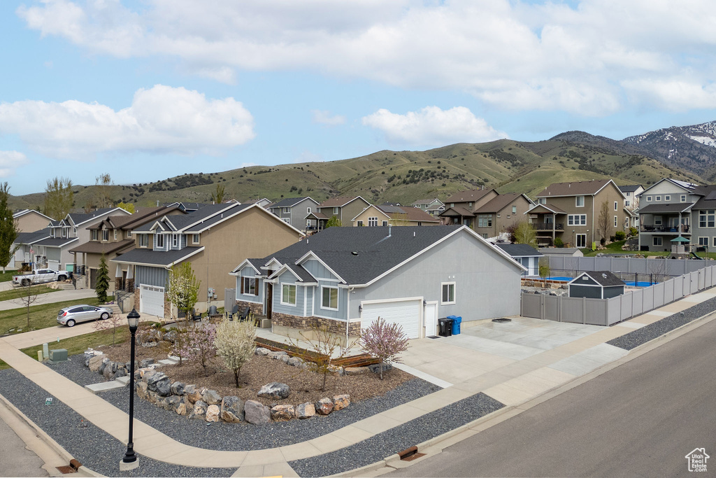 View of front of home featuring a residential view, fence, a mountain view, and concrete driveway