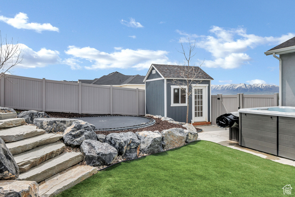 View of yard with a fenced backyard, an outdoor structure, and a trampoline