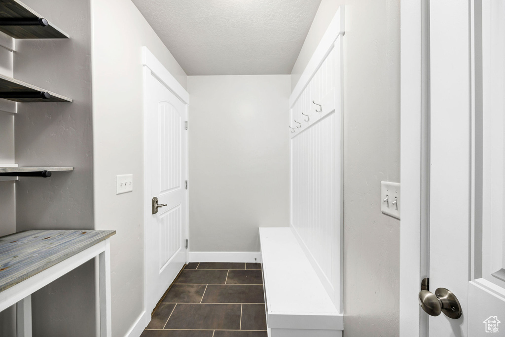 Mudroom with dark tile patterned floors, a textured ceiling, and baseboards