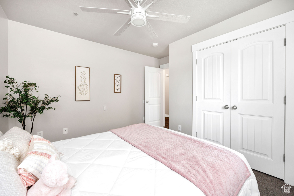 Bedroom featuring a closet, a ceiling fan, and dark carpet