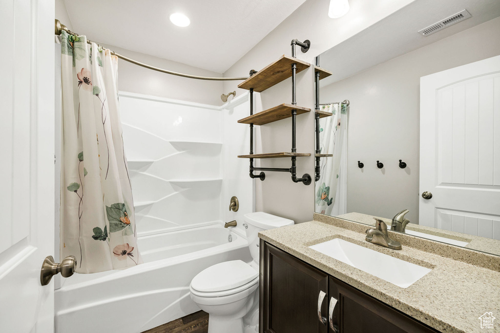 Full bath featuring visible vents, vanity, wood finished floors, shower / bath combination with curtain, and toilet