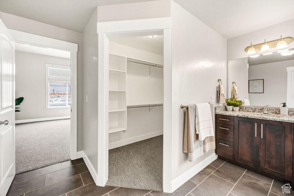 Bathroom featuring baseboards, a spacious closet, tile patterned flooring, and vanity