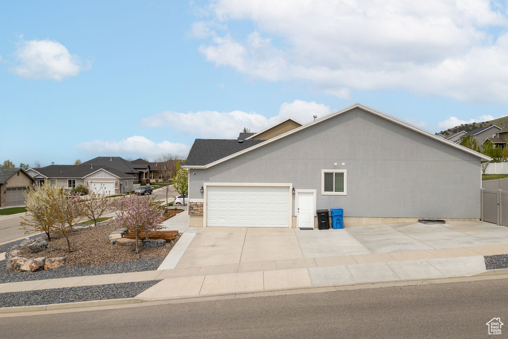 View of home\\\'s exterior featuring a garage, roof with shingles, a residential view, and concrete driveway