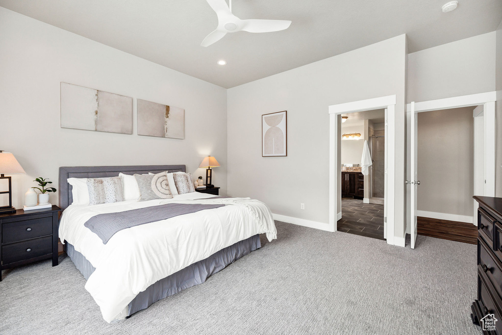 Bedroom with baseboards, light carpet, ceiling fan, and ensuite bathroom