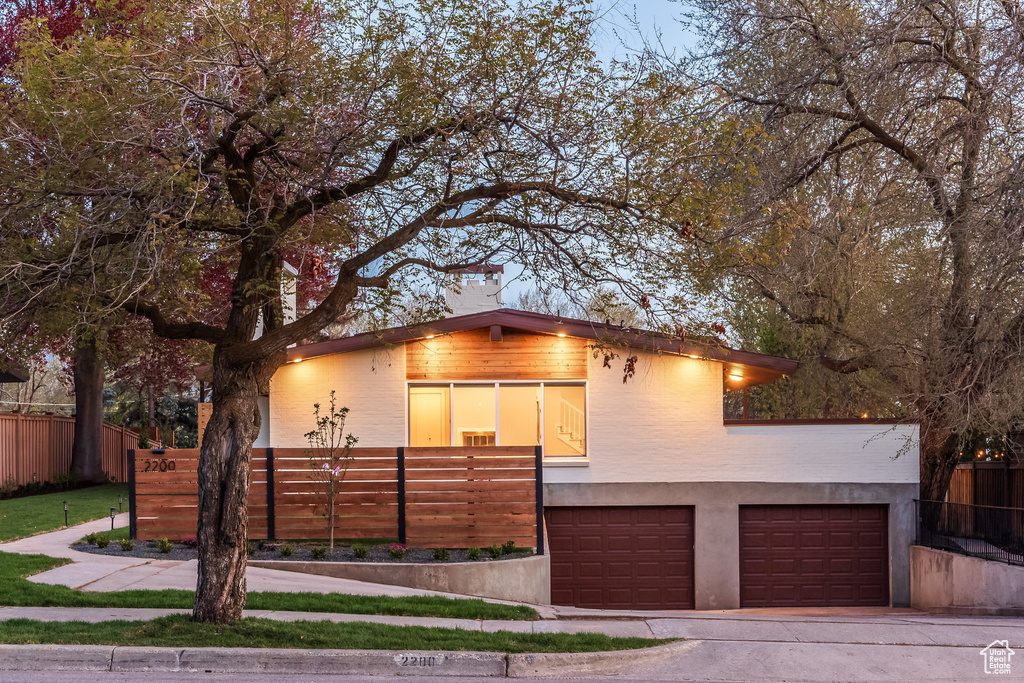 View of front of house featuring stucco siding, fence, driveway, and a garage