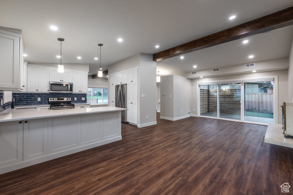 Kitchen with appliances with stainless steel finishes, dark wood finished floors, open floor plan, decorative backsplash, and visible vents