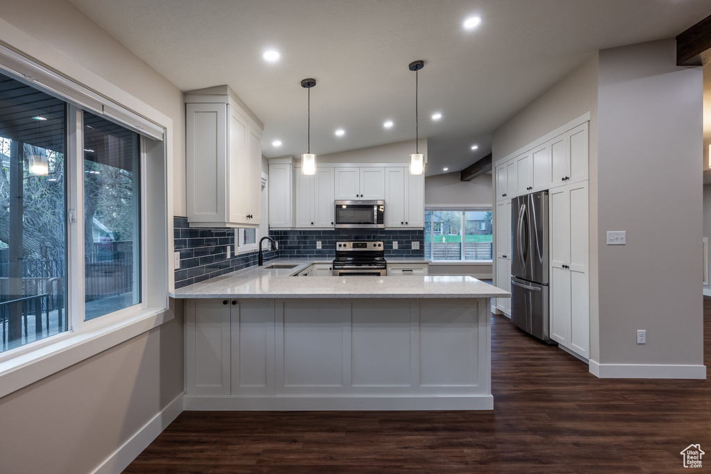 Kitchen with decorative backsplash, a peninsula, baseboards, a sink, and stainless steel appliances