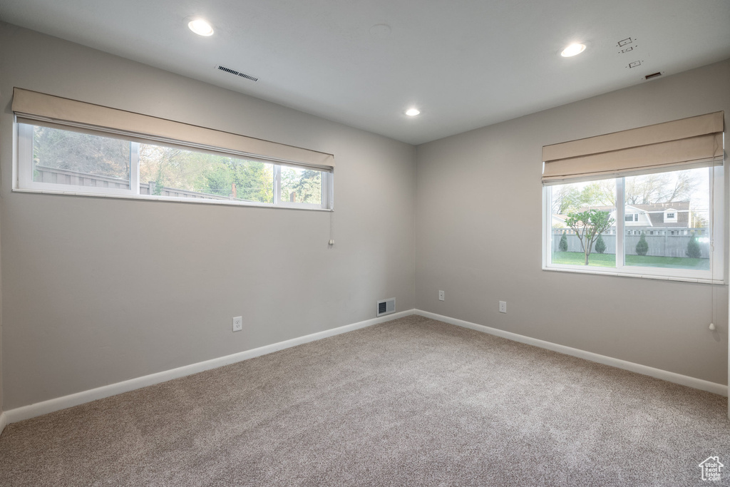 Carpeted empty room featuring baseboards, visible vents, and a wealth of natural light